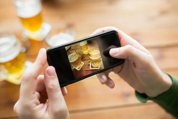 Close up of hands with smartphone picturing beer — Stock Photo, Image