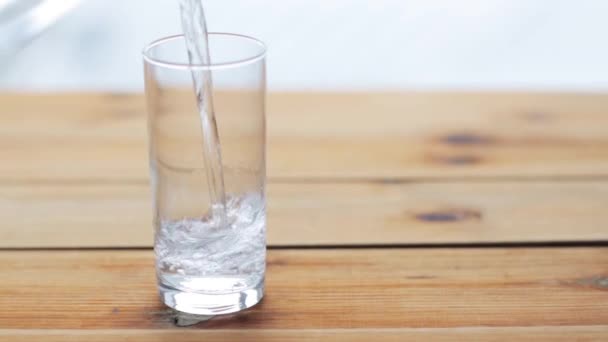 Agua vierte en vidrio sobre mesa de madera — Vídeo de stock