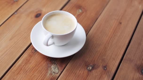 Azúcar cayendo en la taza de café en la mesa de madera — Vídeo de stock