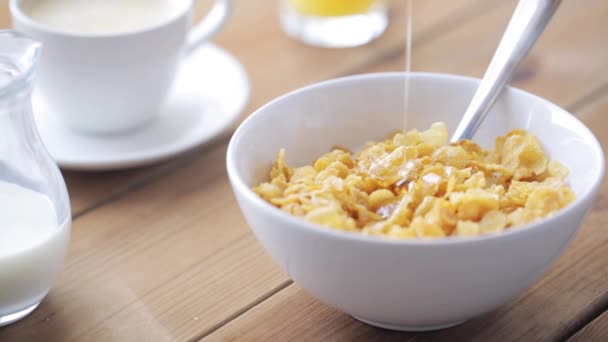 Honing gieten aan cornflakes op houten tafel — Stockvideo