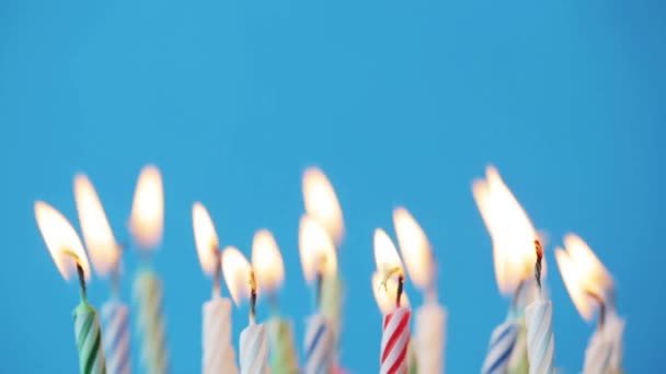 Mavi arka plan üzerinde yanan doğum günü mumları — Stok video