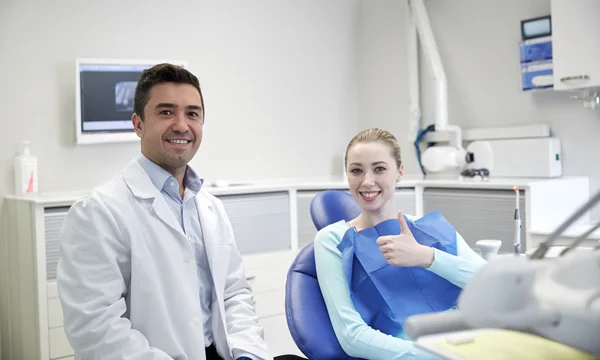 Dentista masculino feliz con paciente mujer en la clínica —  Fotos de Stock