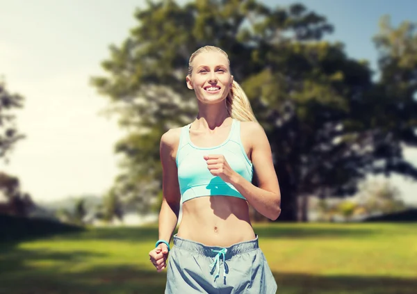 Leende ung kvinna kör eller jogga över parken — Stockfoto