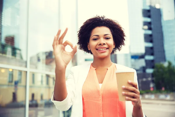 Happy woman with coffee showing ok up in city — Stock Photo, Image