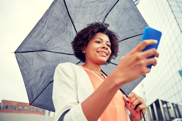 Affärskvinna med paraply textning på smartphone — Stockfoto