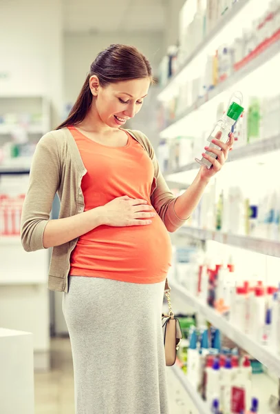 Mujer embarazada feliz elección de loción en la farmacia — Foto de Stock