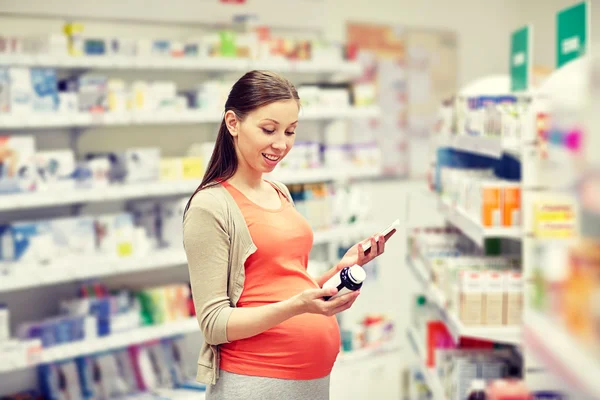 Mujer embarazada feliz con teléfono inteligente en la farmacia —  Fotos de Stock