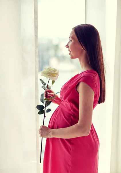 Glad gravid kvinna med rosa blomma hemma — Stockfoto