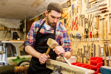 carpenter with wood, hammer and chisel at workshop clipart