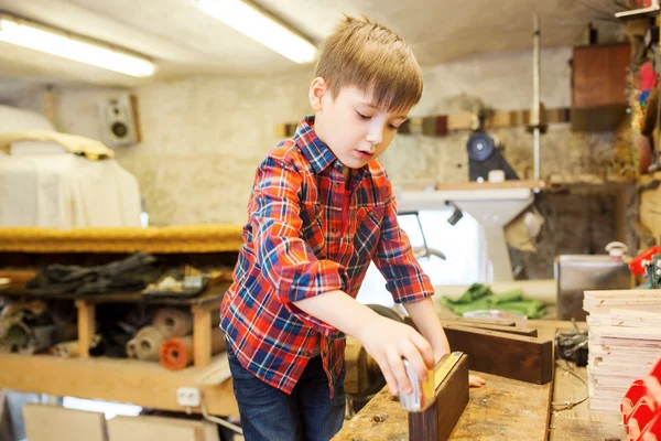 Glad liten pojke med plankan och linjal på verkstad — Stockfoto