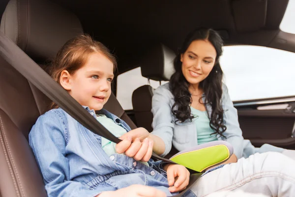 Happy woman fastening child with seat belt in car — Stock Photo, Image