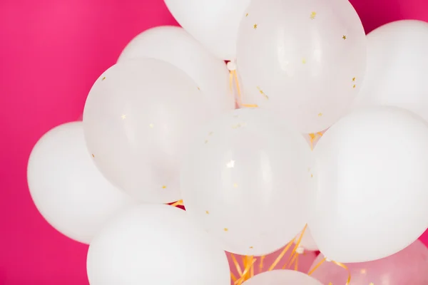 Закрытие белых гелиевых шариков поверх розового — стоковое фото