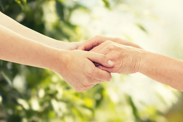 Primer plano de la mujer mayor y joven tomados de la mano — Foto de Stock