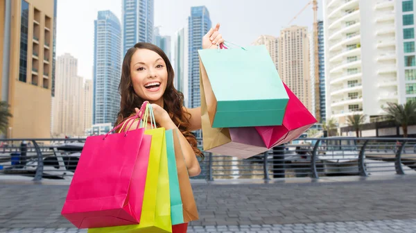 Mujer feliz con bolsas de compras sobre la ciudad de Dubai —  Fotos de Stock