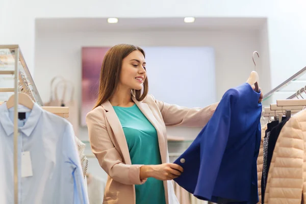 Feliz joven mujer elegir ropa en el centro comercial —  Fotos de Stock