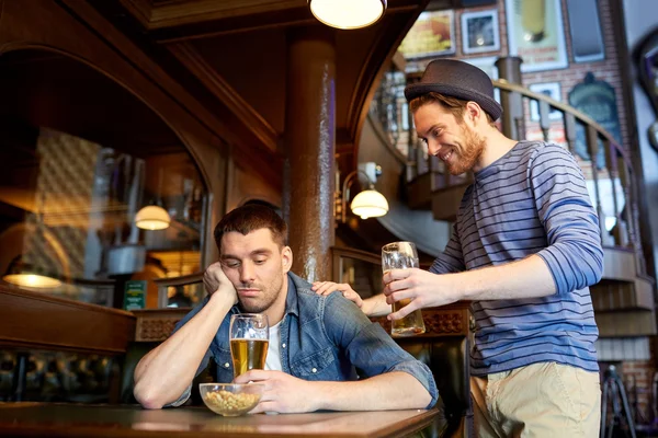Человек с пивом и пьяный друг в баре или пабе — стоковое фото