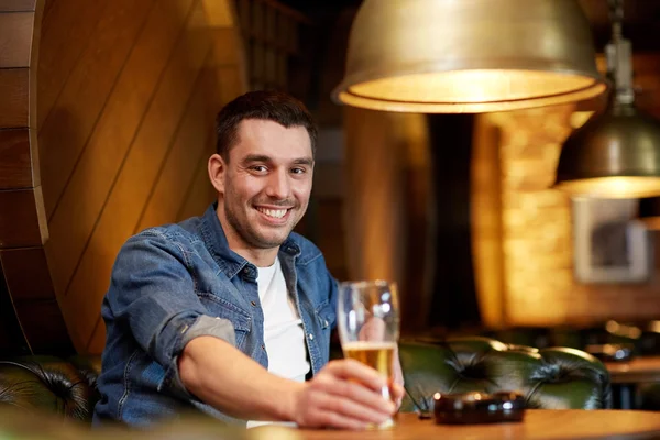 Homem feliz bebendo cerveja rascunho no bar ou pub — Fotografia de Stock