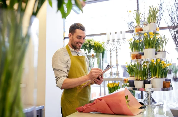 Florist man with clipboard at flower shop counter — Stock Photo, Image