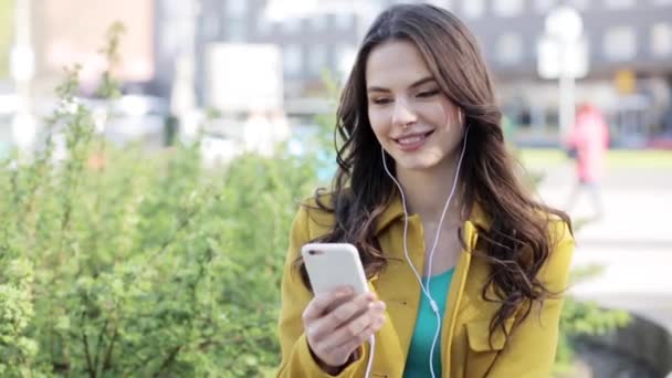 Feliz joven con teléfono inteligente y auriculares — Vídeos de Stock