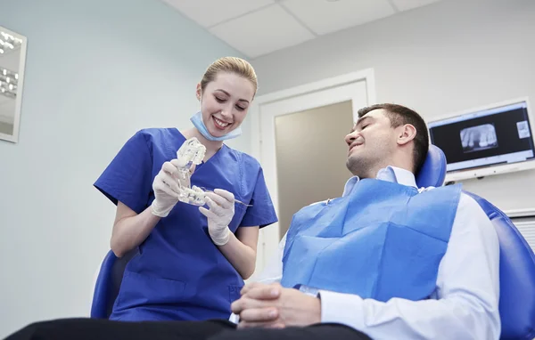 Happy dentist showing jaw layout to male patient — Stock Photo, Image