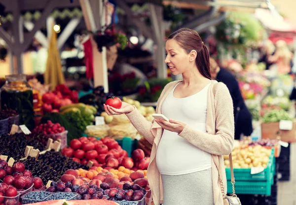 Mujer embarazada con smartphone en el mercado callejero —  Fotos de Stock