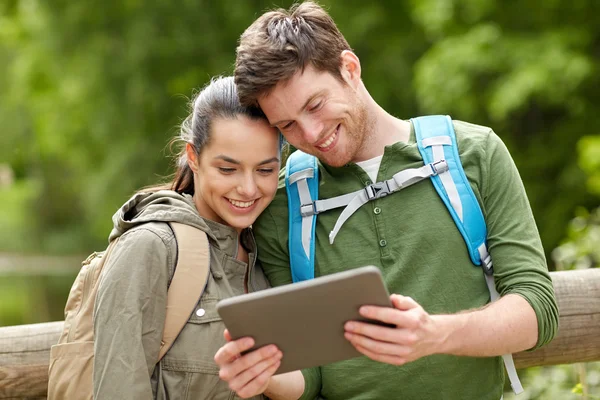 Gelukkige paar met rugzakken en tablet pc buitenshuis — Stockfoto