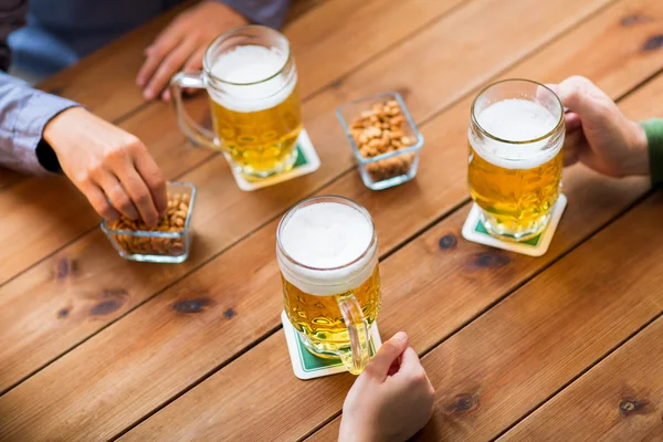 Zbliżenie dłoni z kufle do piwa w barze lub pubie — Zdjęcie stockowe