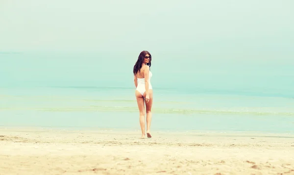 Молодая женщина в купальнике прогулка по пляжу — стоковое фото