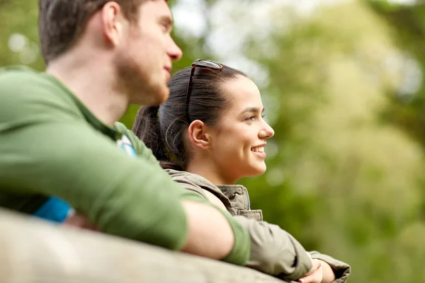 Usmívající se pár s batohy na mostě v přírodě — Stock fotografie
