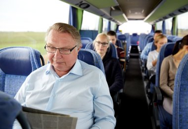 happy senior man reading newspaper in travel bus clipart