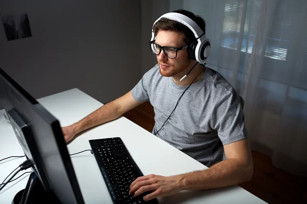 Muž v sluchátka hrát počítačové video hru doma — Stock fotografie