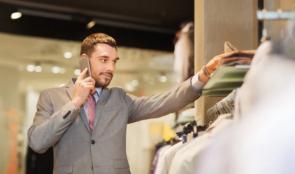 Lycklig man uppmanar smartphone på klädaffär — Stockfoto