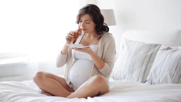 Pregnant woman eating croissant in bed at home 47 — Stock Video