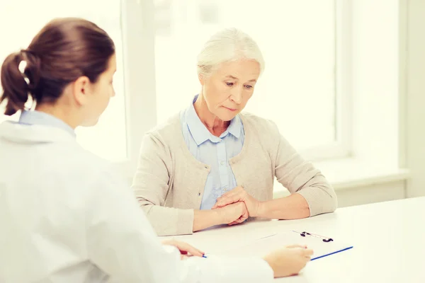 Arzt mit Klemmbrett und Seniorin im Krankenhaus — Stockfoto