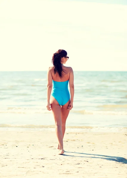 Jonge vrouw in zwembroek wandelen op het strand — Stockfoto