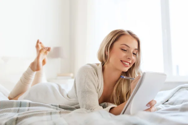 Felice giovane donna con taccuino a letto a casa — Foto Stock