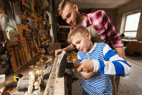 Pai e filho com martelo trabalhando na oficina — Fotografia de Stock