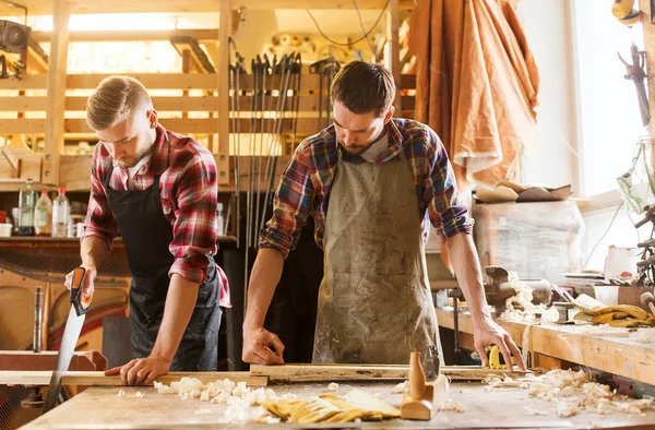 Carpinteros que trabajan con sierra y madera en el taller —  Fotos de Stock