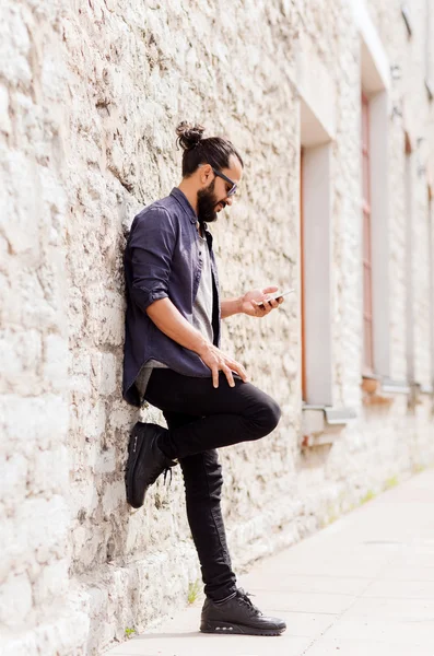 Hombre mensaje de texto en el teléfono inteligente en la pared de piedra — Foto de Stock