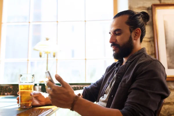 Homem com smartphone bebendo cerveja no bar ou pub — Fotografia de Stock