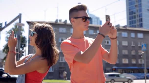 Feliz pareja adolescente con teléfonos inteligentes en la ciudad — Vídeos de Stock