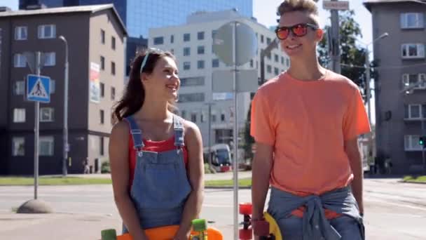 Εφηβικό ζευγάρι με σανίδες δεκάρα περπατώντας στην πόλη — Αρχείο Βίντεο