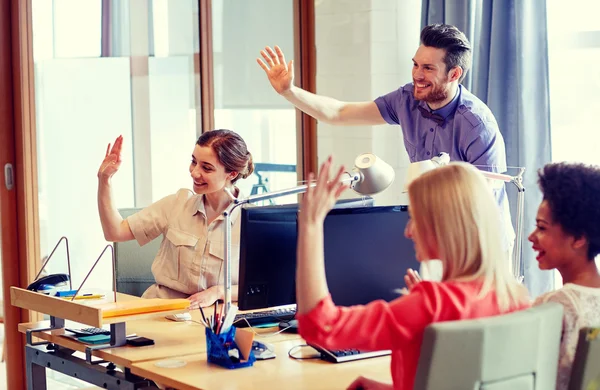 Gelukkig creatieve team zwaaien handen in office — Stockfoto