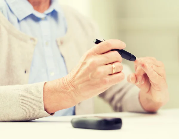 Senior vrouw met glucometer controleren bloedsuikerspiegel — Stockfoto