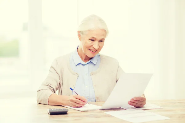 Seniorin mit Papieren und Taschenrechner zu Hause — Stockfoto