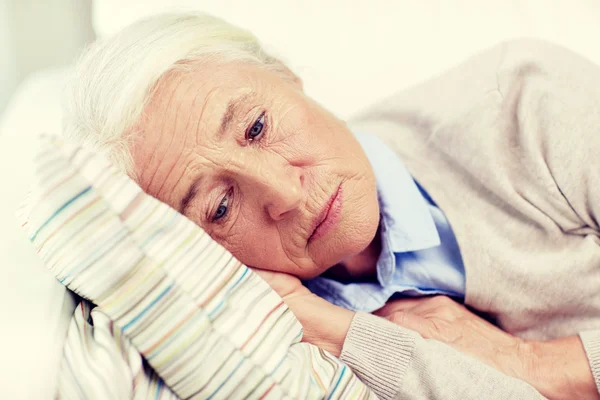 Сумна старша жінка лежить на подушці вдома — стокове фото