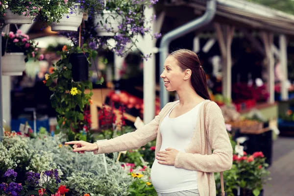 Mujer embarazada eligiendo flores en el mercado callejero —  Fotos de Stock