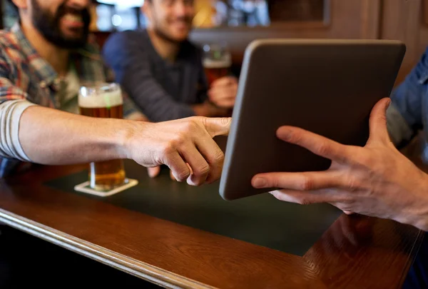 Крупные планы мужчин с планшетным компьютером и пивом в баре — стоковое фото