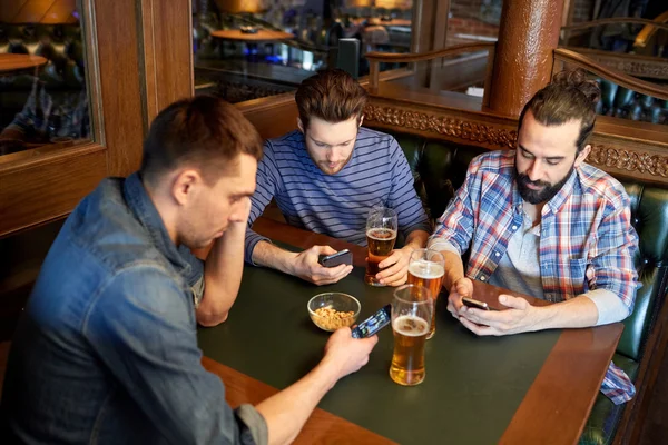 Homens com smartphones bebendo cerveja no bar ou pub — Fotografia de Stock