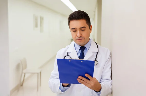 Doctor writing to clipboard at hospital — Stock Photo, Image